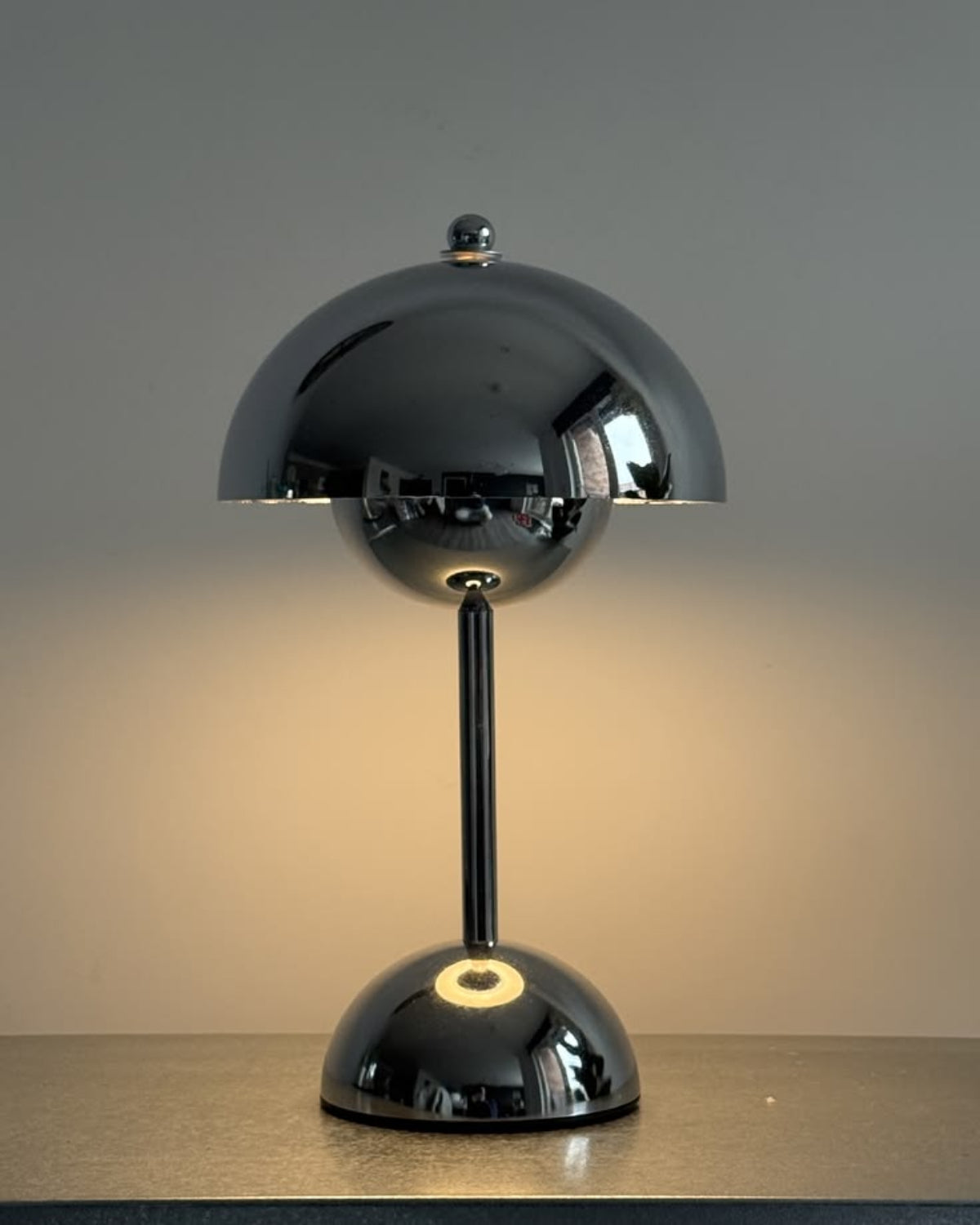 Black table lamp with a reflective surface on a neutral background